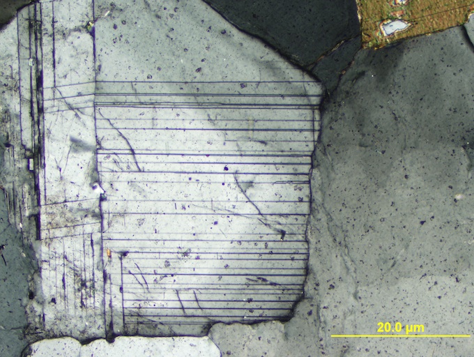 These thin section images clearly demonstrate the inclined extinction of Plagioclase as the microscope stage is rotated approximately 45º. The characteristic twinning of Plagioclase is also visible. 